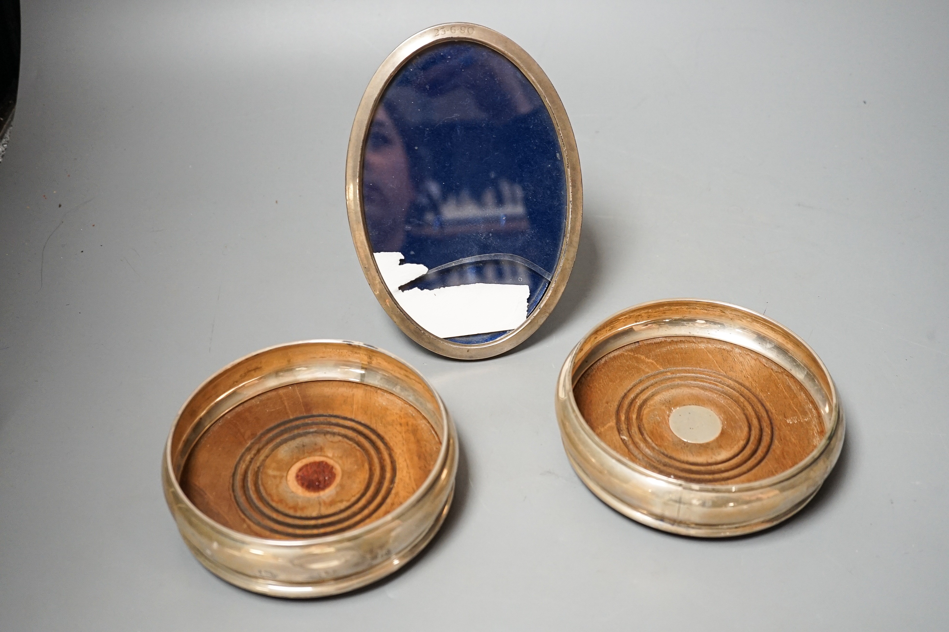A pair of modern silver mounted wine coasters, W.E.V. London, 1990, (a.f.), 12.2cm and a 925 mounted oval photograph frame.